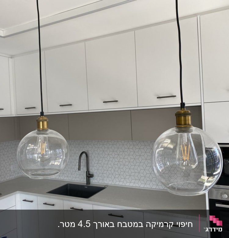 מטבח משופץ עם ארונות לבנים ותאורה תלויה